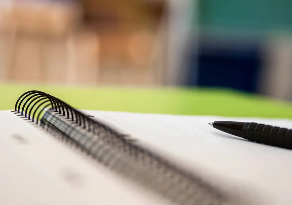 Notizbuch mit Stift auf grünem Untergrund